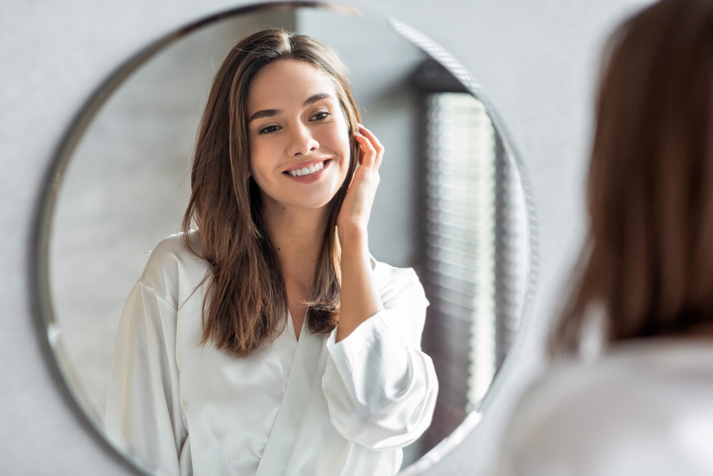 Woman looking in the mirror after microneedling in Georgetown, KY